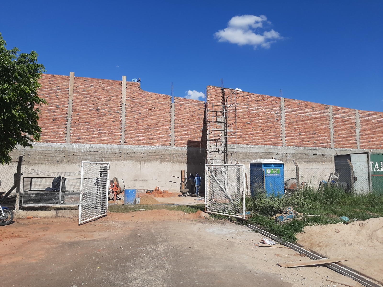 Vista externa da alvenaria das salas em construção, com andaime tubular